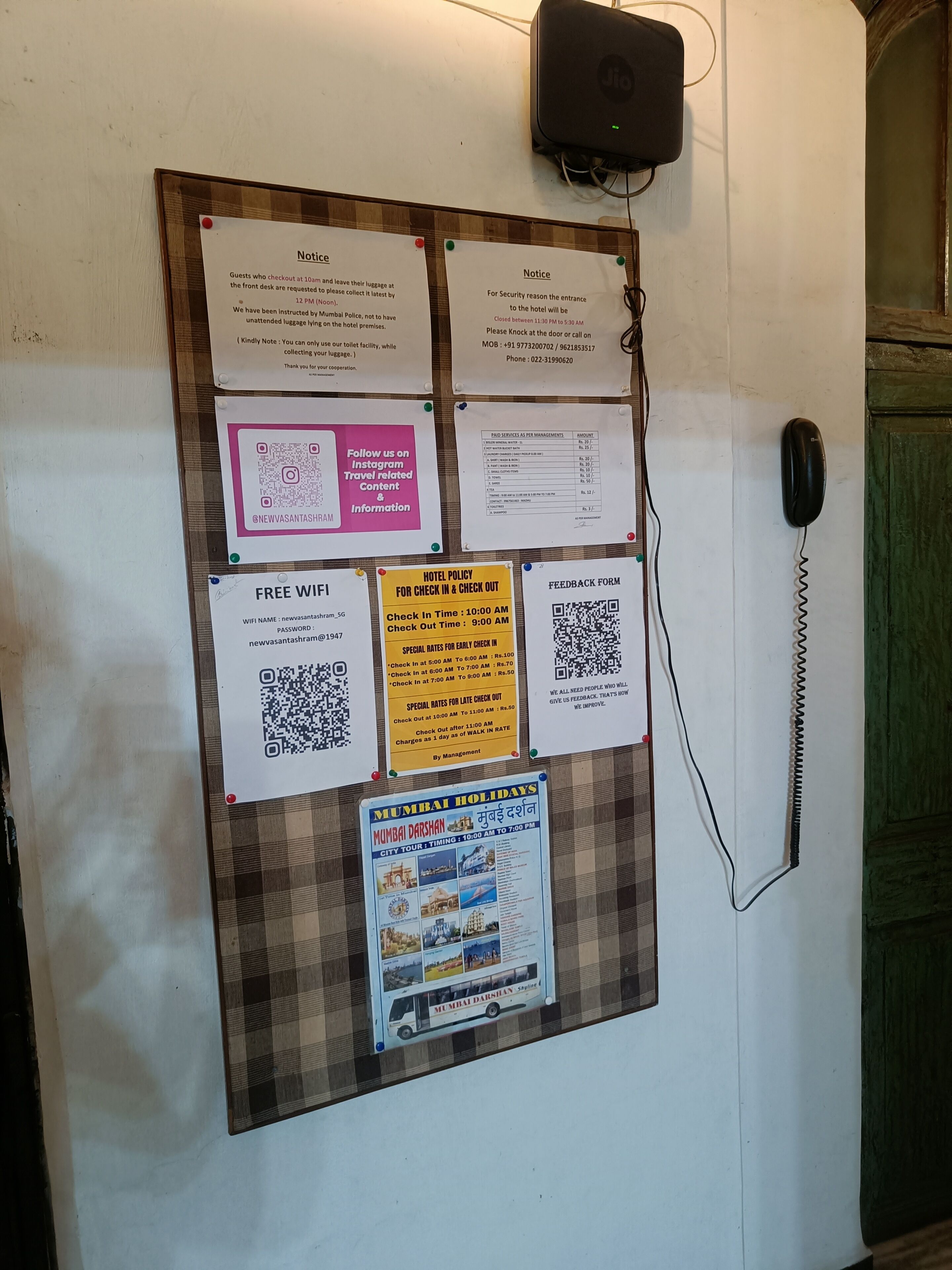 A bulletin board with various notices and information for hotel guests, including check-in and check-out times, WiFi details, and a feedback form.