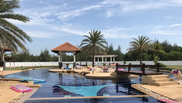 Una piscina con sillas de descanso y un pabellón.