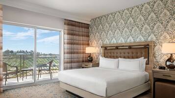 Quarto de hotel com uma cama grande, duas mesas de cabeceira com luminárias, vista para o exterior através de uma porta de correr e papel de parede estampado.