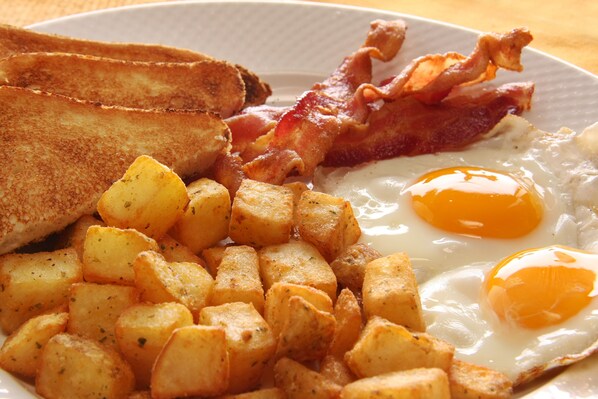A plate with fried eggs, bacon, toast, and diced potatoes. - The Cassara Carlsbad, Tapestry Collection by Hilton (Carlsbad)