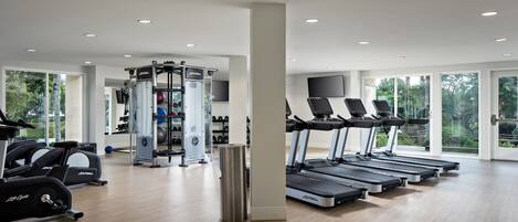 A modern gym with treadmills, elliptical machines, and weightlifting equipment.