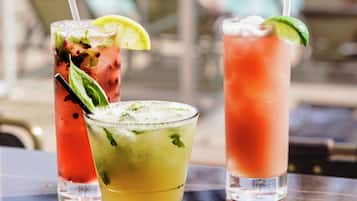 Three cocktails on a table with a pool view in the background.