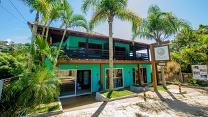A two-story building with a green facade, a balcony, and a sign indicating it is a hotel. - Kalani Pousada (Imbituba)