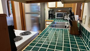 A compact kitchen with a gas stove, stainless steel refrigerator, and a microwave. - Nature Retreat in Juneau-Near Town, Sleeps 4. (Juneau)