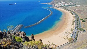 A coastal town with a beach, rocky shoreline, and a large ship in the distance. - HomeForGuest Design Attic Apartment, FREE parking (Santa Cruz de Tenerife)