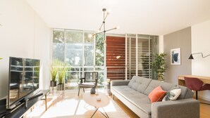 A modern living room with a sofa, TV, and plants. - HomeForGuest Design Attic Apartment, FREE parking (Santa Cruz de Tenerife)
