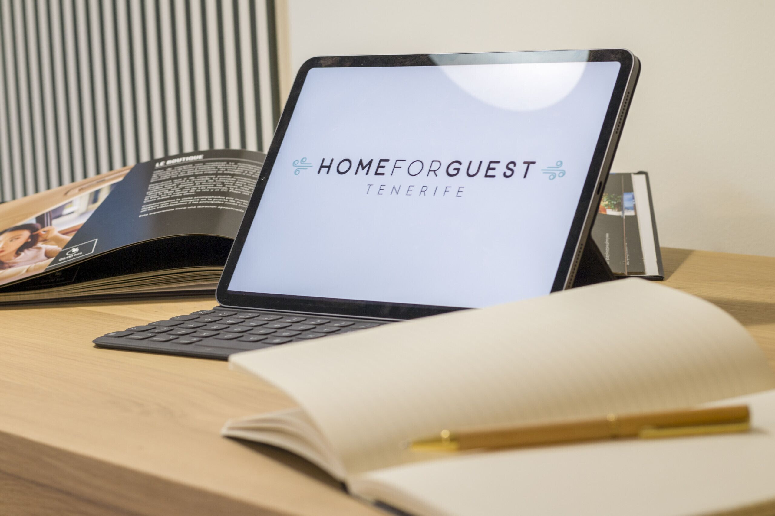 A laptop on a desk with a screen displaying 'HOMEFORGUEST TENERIFE'.