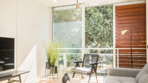 A modern living room with a large window, a sofa, a coffee table, and a TV. - HomeForGuest Design Attic Apartment, FREE parking (Santa Cruz de Tenerife)