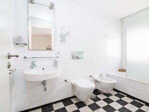A modern bathroom with a white sink, toilet, bidet, and a large mirror. - HomeForGuest Design Attic Apartment, FREE parking (Santa Cruz de Tenerife)