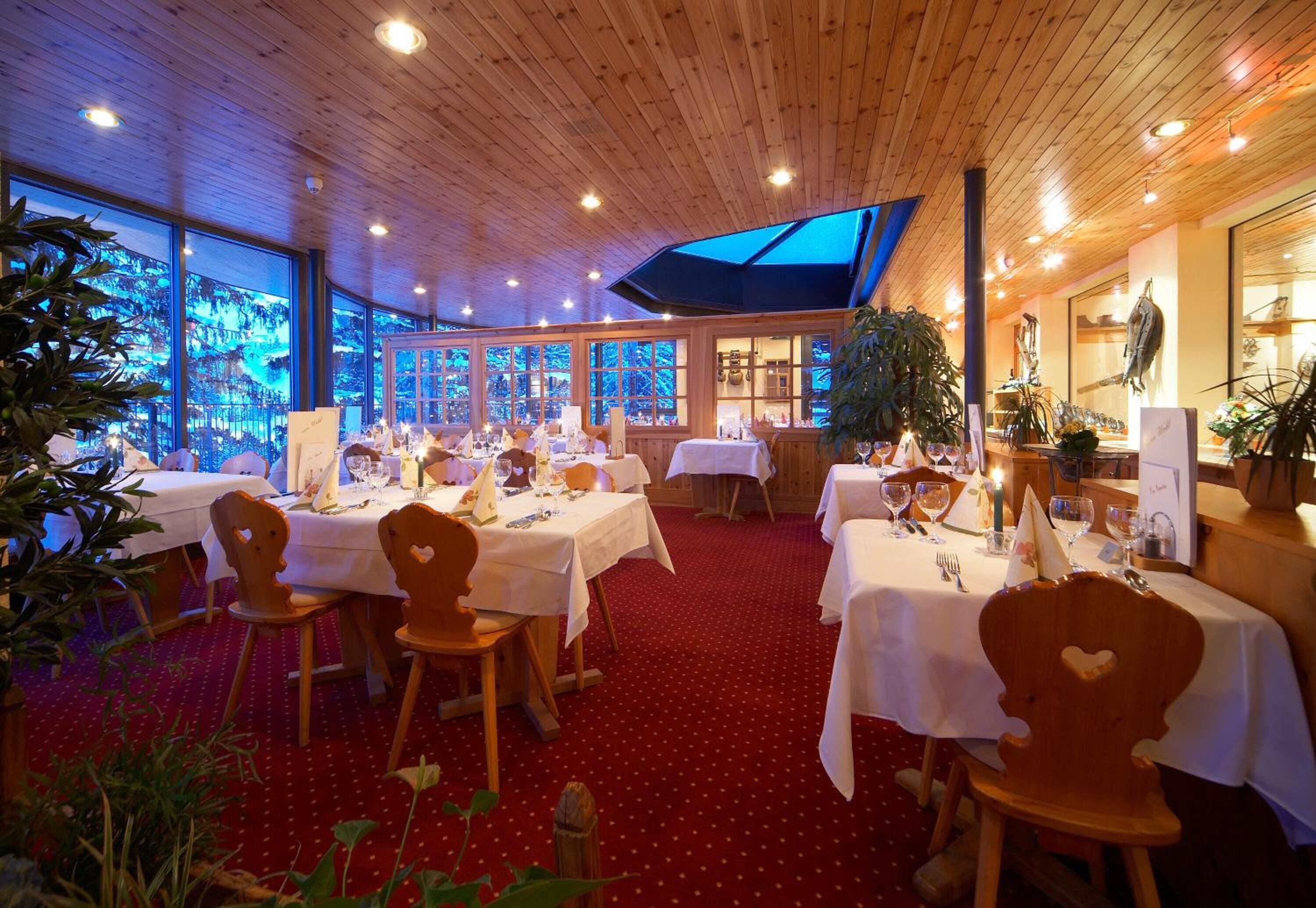 A restaurant with wooden interiors, white tablecloths, and red carpet flooring.