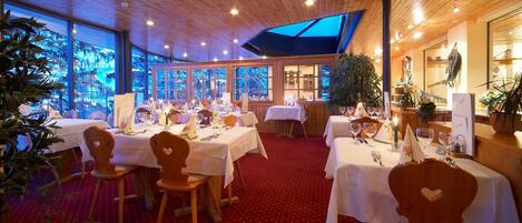 A restaurant with wooden interiors, white tablecloths, and red carpet flooring.