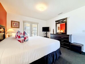 A hotel room with a large bed, a television, a dresser, and a mirror. - Stylish Pool Close To Withlacoochee Bike Trail 3 Bedroom Home by RedAwning (Inverness)