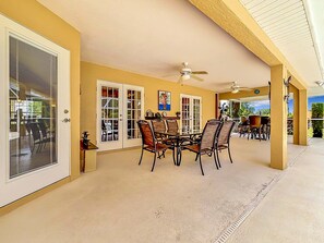 A covered patio area with a dining table and chairs, a ceiling fan, and a view of the outdoors. - Stylish Pool Close To Withlacoochee Bike Trail 3 Bedroom Home by RedAwning (Inverness)