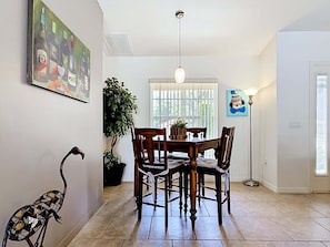 Un comedor con una mesa y sillas, una planta en maceta y un cuadro en la pared.