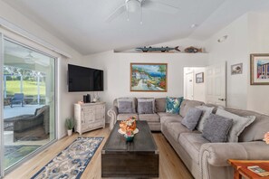 A living room with a sofa, coffee table, TV, and artwork on the wall.