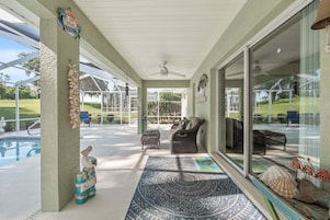 Un área de patio techada con piscina, muebles de mimbre y conchas decorativas.