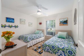 A bedroom with two beds, a ceiling fan, a window with blinds, and wall decorations. - Little Peace Of Paradise At Willow Wood 3 Bedroom Home by RedAwning (Inverness)
