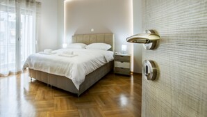 A modern bedroom with a large bed, bedside tables, and a wooden floor. - Spacious 3-Bedroom Apartment Near the Train (Athens)