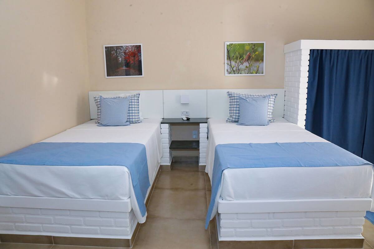 Una habitación de hotel con dos camas individuales, una mesita y una mesita de noche.