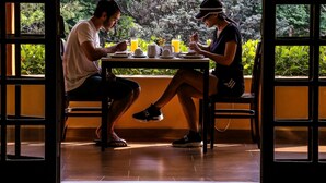 Dos personas cenando en una mesa con vistas a la exuberante vegetación a través de amplios ventanales.