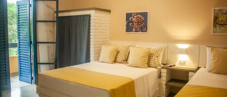 A hotel room with a large bed, a bedside table with a lamp, a window with curtains, and a picture on the wall.