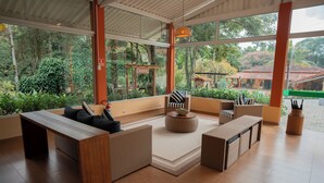 Un interior moderno con mostrador de recepción de madera, zona de estar y amplios ventanales que ofrecen vistas al exterior.