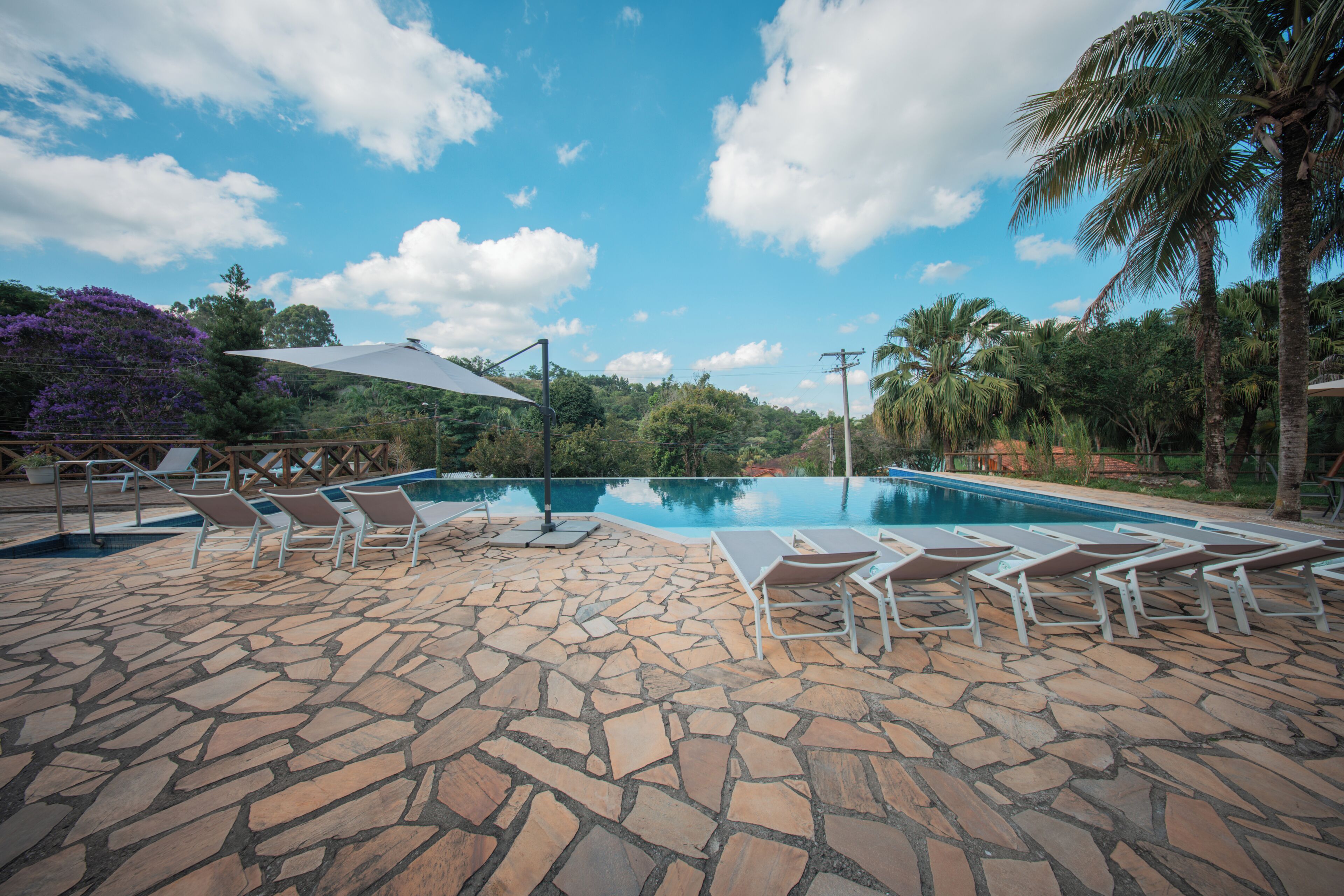 A swimming pool with lounge chairs and a stone patio.