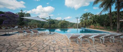 A swimming pool with lounge chairs and a stone patio.