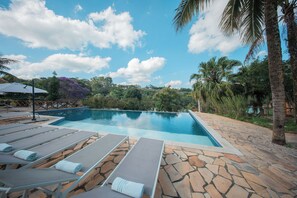A swimming pool with lounge chairs, surrounded by stone tiles and palm trees. - Matiz Igaratá Resort, Spa e Eventos (Igarata)