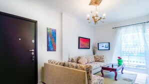Un salon avec un canapé, une table basse et une porte. Deux tableaux encadrés sont accrochés au mur.