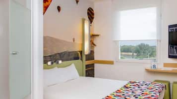 Habitación de hotel con cama, ventana con vistas, televisor y un cuadro de paisaje montañoso en la pared.