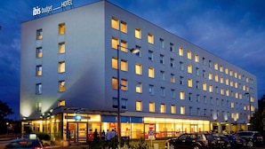 Un moderno edificio de hotel con fachada plana, múltiples ventanas y un cartel que indica que es un hotel ibis budget.