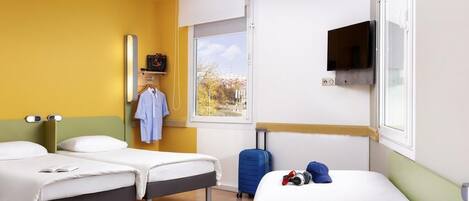 A hotel room with two beds, a window with a view, a TV, and a suitcase.