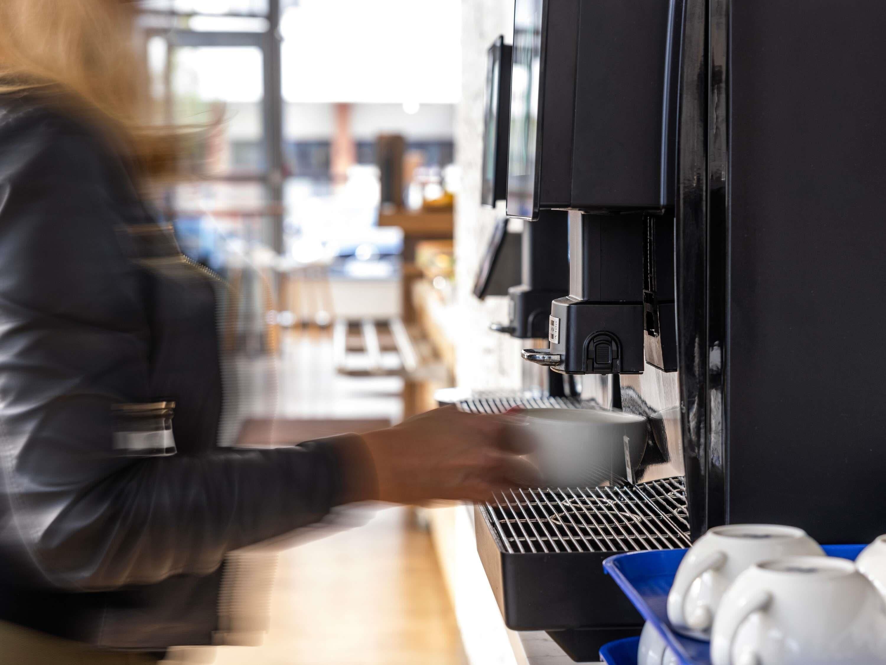 A person operating a coffee machine in a commercial setting.