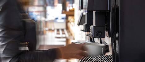 A person operating a coffee machine in a commercial setting.