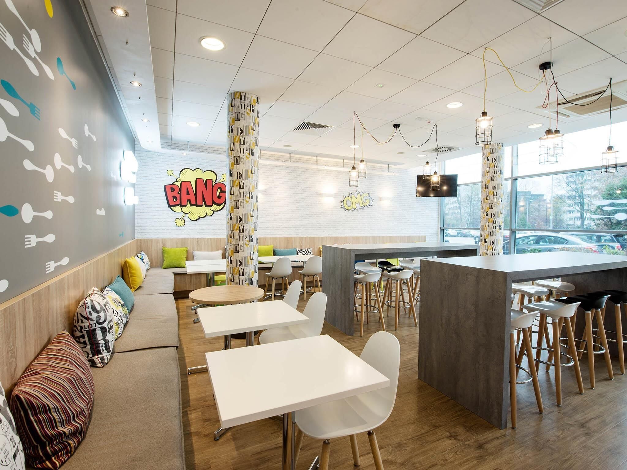 A modern restaurant interior with a bar area, seating arrangements, and a wall with food-related graphics.