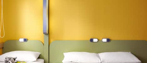 Una habitación de hotel con dos camas, una mesita de noche, una lámpara y un peluche.