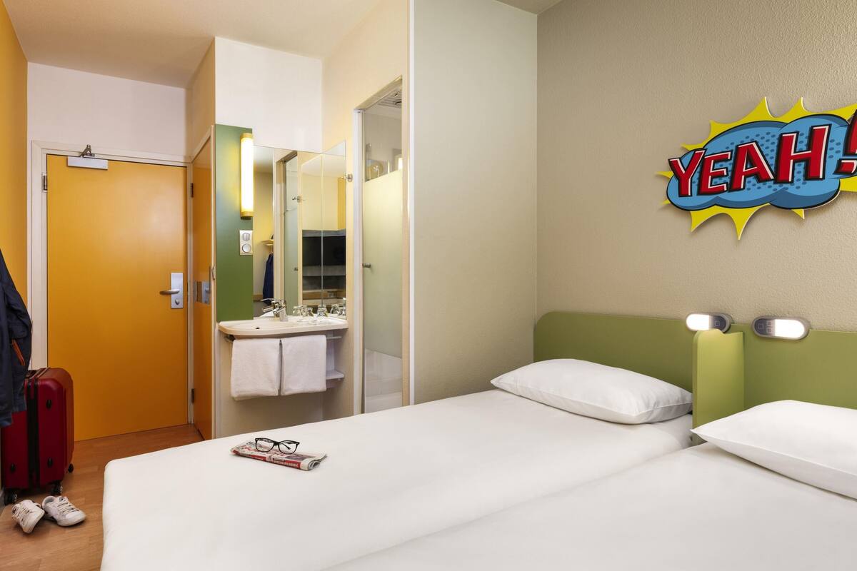 A hotel room with a bed, a bathroom with a sink, and a mirror.