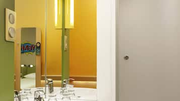 A bathroom with a mirror, two vertical light fixtures, a sink with a chrome faucet, and a door.