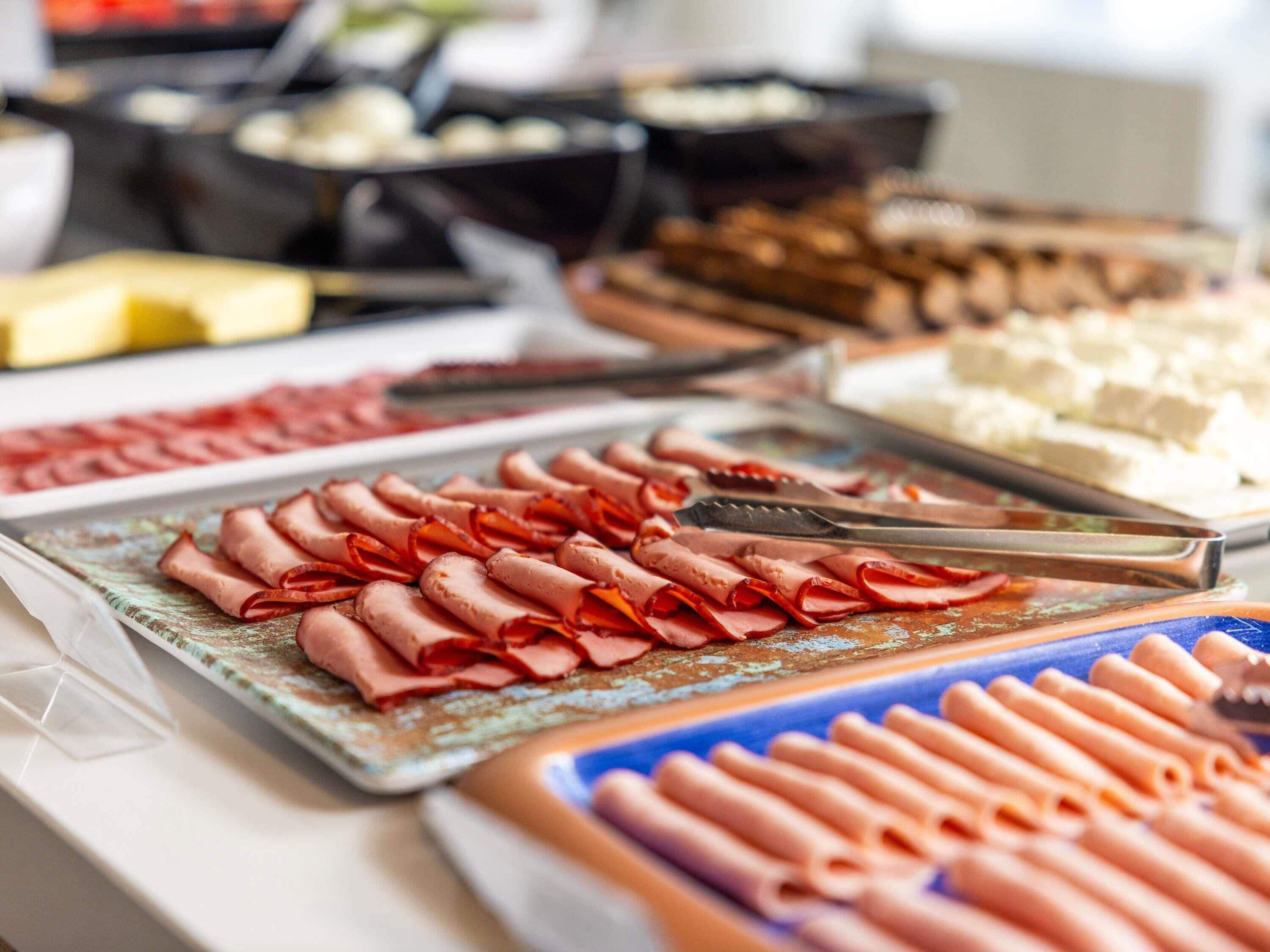 A buffet with various food items including sliced meats and cheeses.