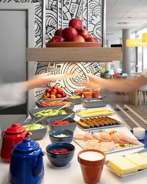 Una mesa de buffet con diversos alimentos y una mano alcanzando un bol.