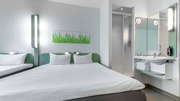 Habitació d'hotel amb un llit, un bany amb un lavabo i mirall, i una decoració mural verda.