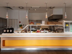 Un buffet moderne proposant une grande variété de plats et d’accompagnements, notamment des pots de sauces et des paniers de fruits.