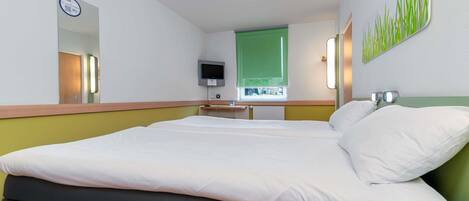 Una habitación de hotel con una cama, televisión, espejo y pared verde.