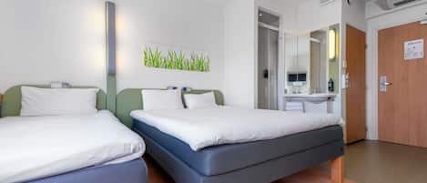 A hotel room with two beds, a bathroom with a mirror, and an air conditioning unit.