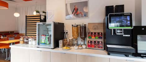 A coffee station with a refrigerator, coffee machine, and a variety of coffee pods.