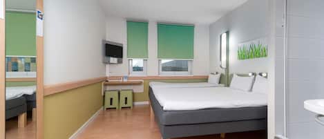 Una habitación de hotel con cama, escritorio, espejo y baño.
