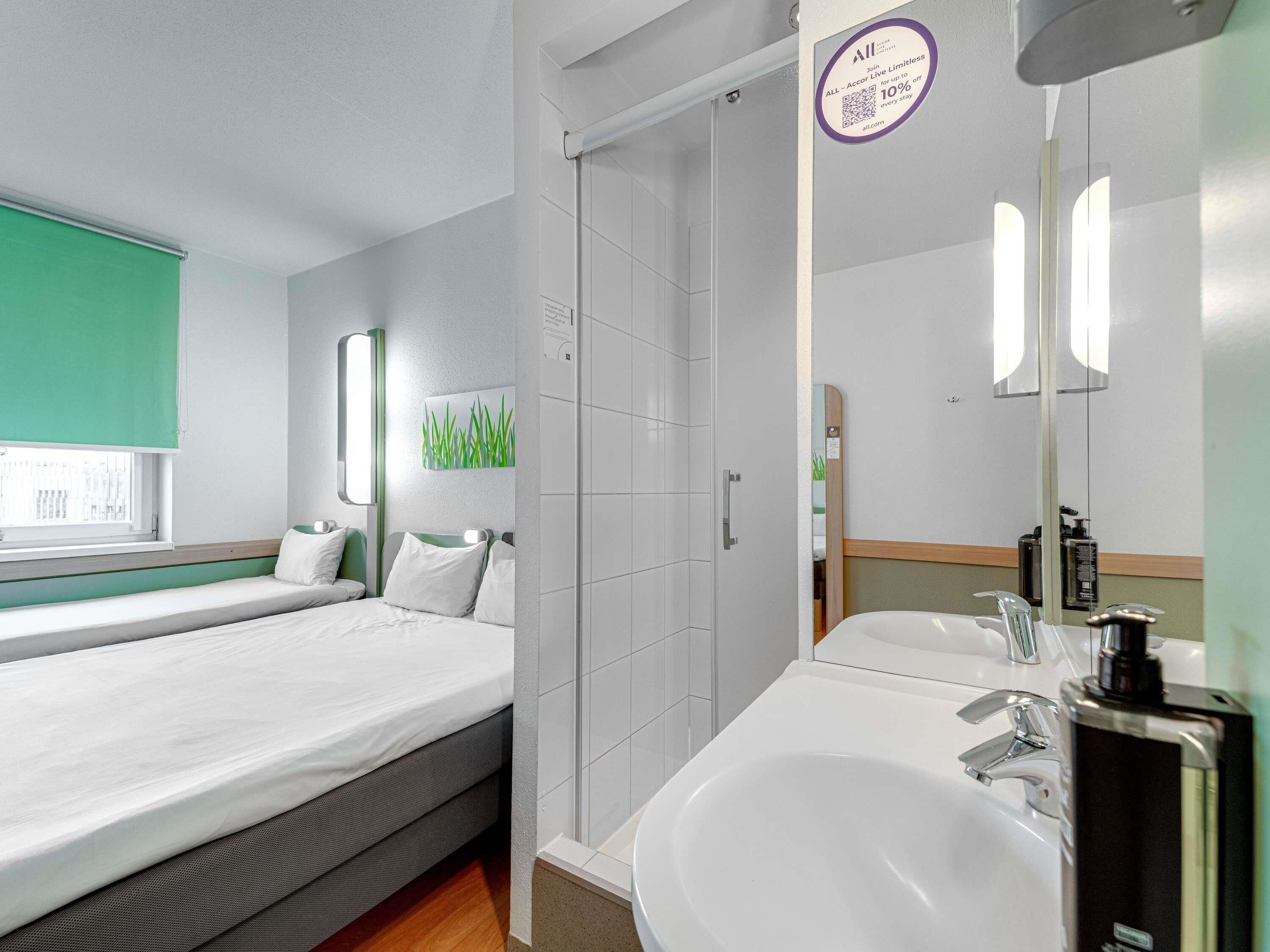 Una habitación de hotel con cama, ducha y lavabo.