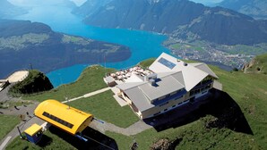A mountain lodge with a large building, a yellow bus, and a lake. - APART HOLIDAYS Morschach (Morschach)