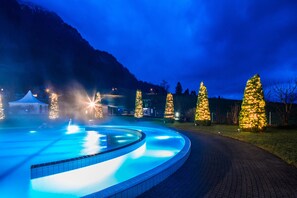 A swimming pool with a curved edge, surrounded by a paved walkway. - APART HOLIDAYS Morschach (Morschach)